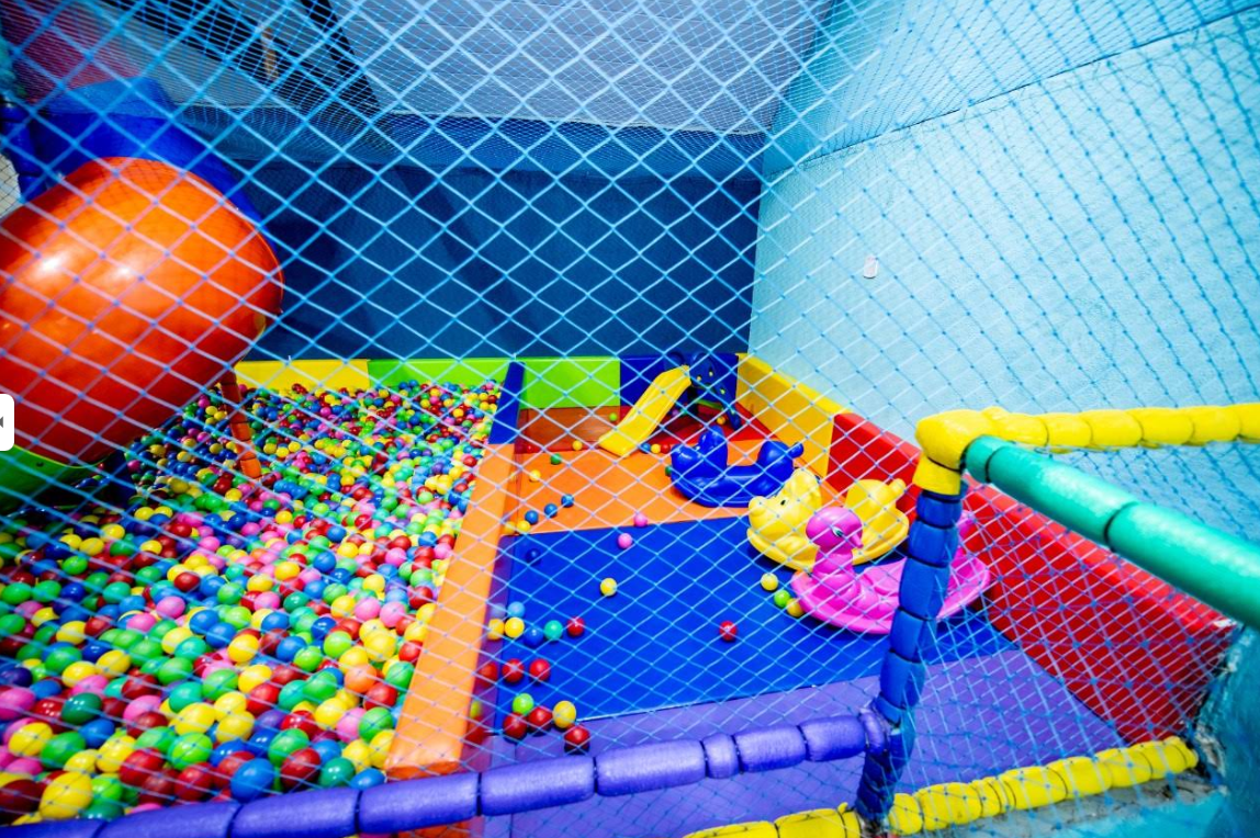 Tobogã espiral laranja caindo na piscina de bolinhas com área baby na Vila Encantada